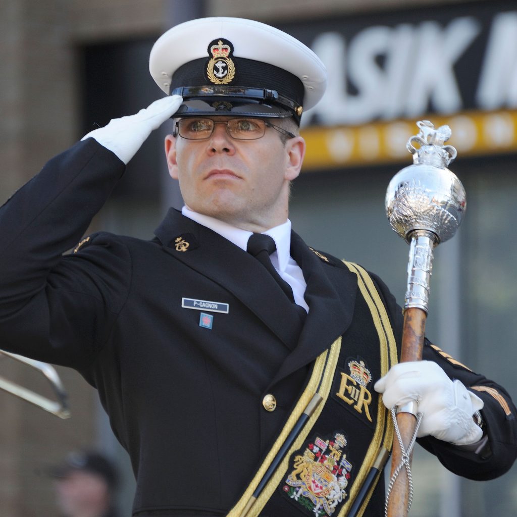 Petty Officer 2nd Class (PO2) David P-Gagnon salutes while passing the dais at Centennial Square