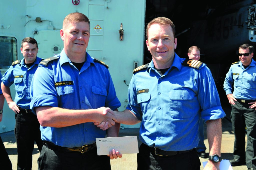 PO1 Robert Franklin receives his cash prize for weighing in at first place for the “Biggest Loser” competition. A fitness challenge where members pushed themselves to lose weight and get fit while at sea.