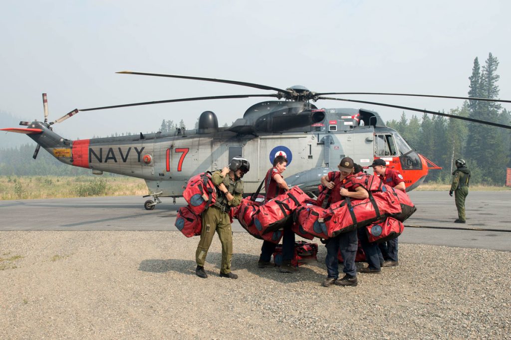 Members of the British Columbia Forest Service pick up their bags after being dropped off by a Sea King in support of OP LENTUS Aug. 21. Photo by Cpl Jeffrey Clement