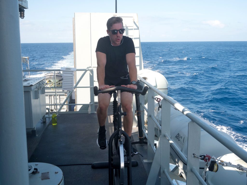 A crew member takes advantage of the nice weather to work out on the bridge wing.