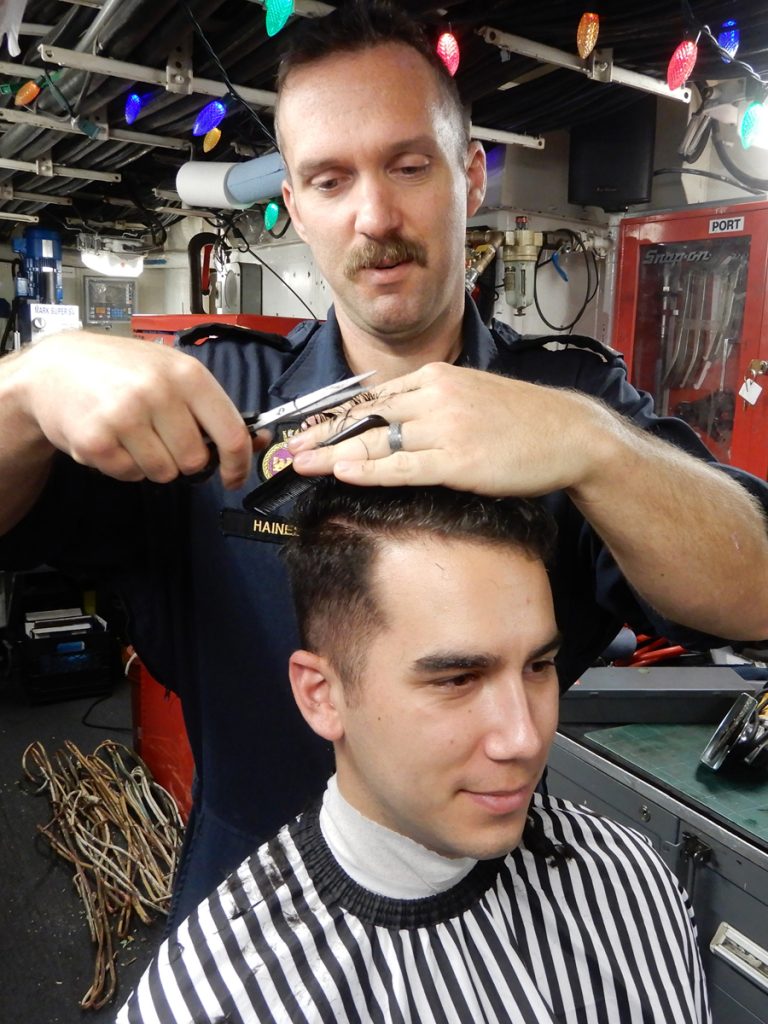 LS Tyler Steffan gets a hair cut from MS Jeffrey Haines as part of a fundraiser for children’s sports charity Jump Start.  Photo by LS Thrun