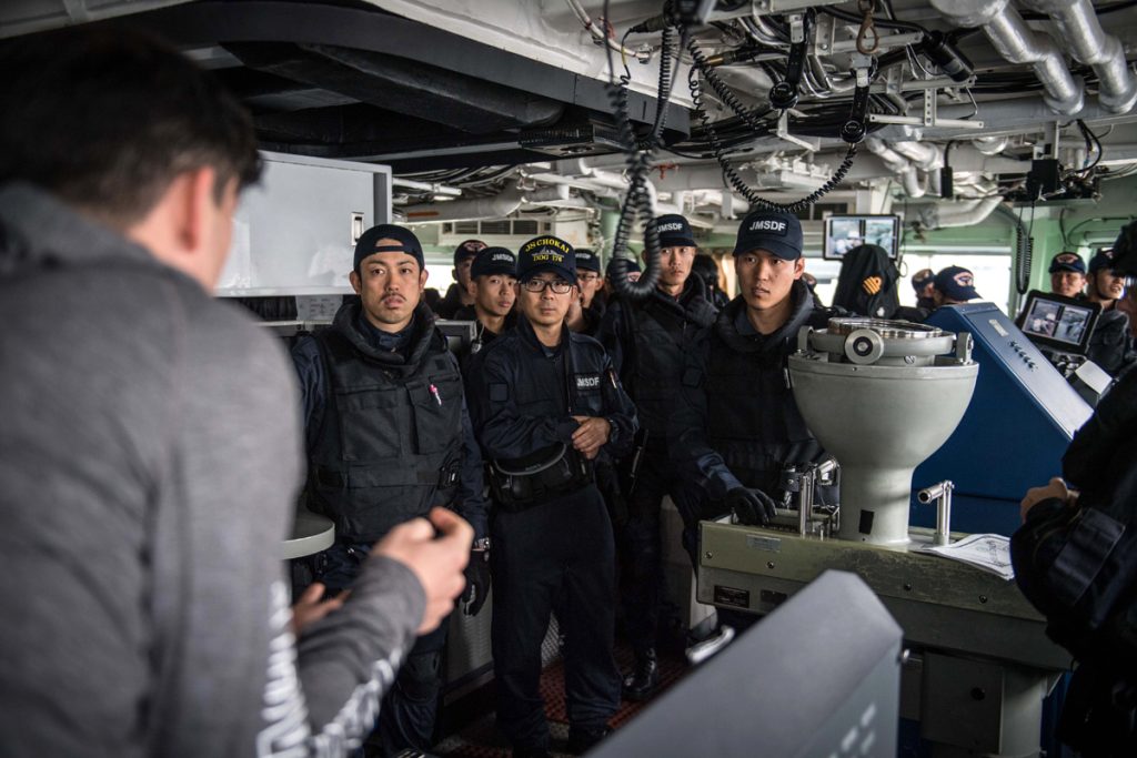 Sub-Lieutenant Riley Perrior discusses Ottawa’s Boarding Party techniques with members of the Japan Maritime Defense Force during a joint naval boarding party exercise onboard HMCS Ottawa on October 16 alongside Yokosuka