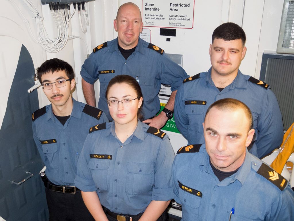 HMCS Ottawa’s starboard watch sonar operators gather for a group photo outside their restricted workspace. Back row: PO2 St. Pierre and LS Buss. Front row: OS Legg