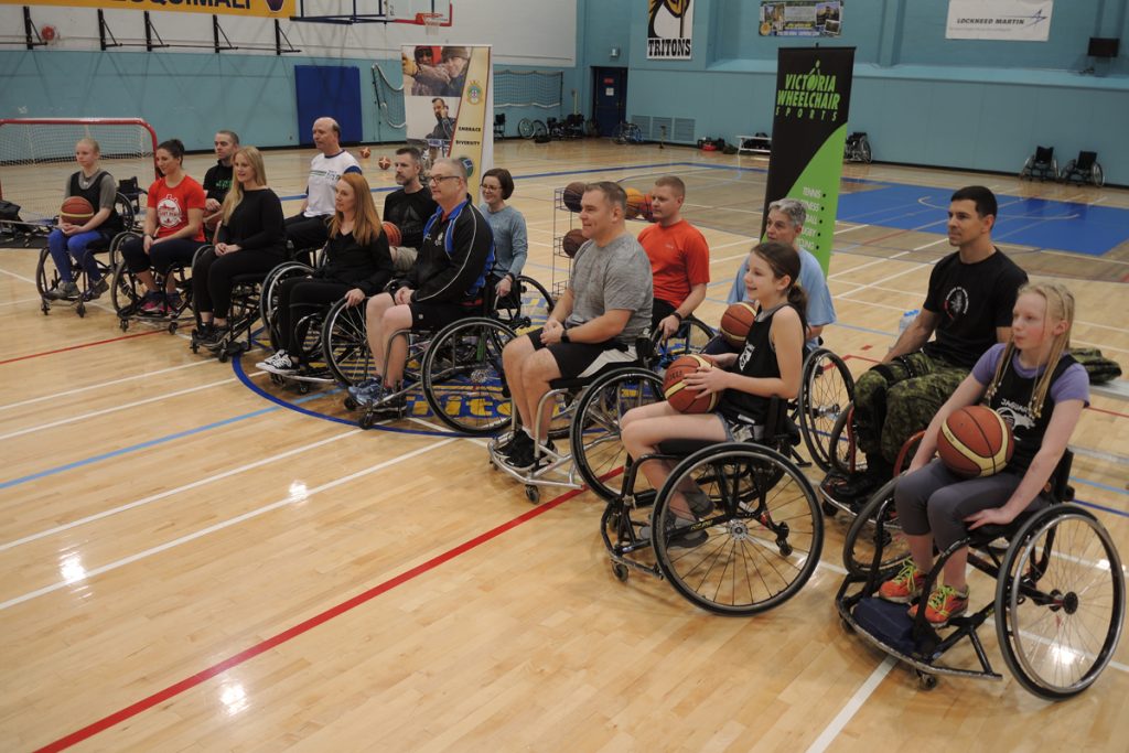 Participants gather for a group photograph prior to the wheelchair basketball game at the Naden Athletic Centre on Dec. 3. The wheelchair sports event was part of CFB Esquimalt’s recognition of International Day of Disabled Persons 2019. Left: Base Commander Captain (Navy) Sam Sader shares a laugh with Simon Cass