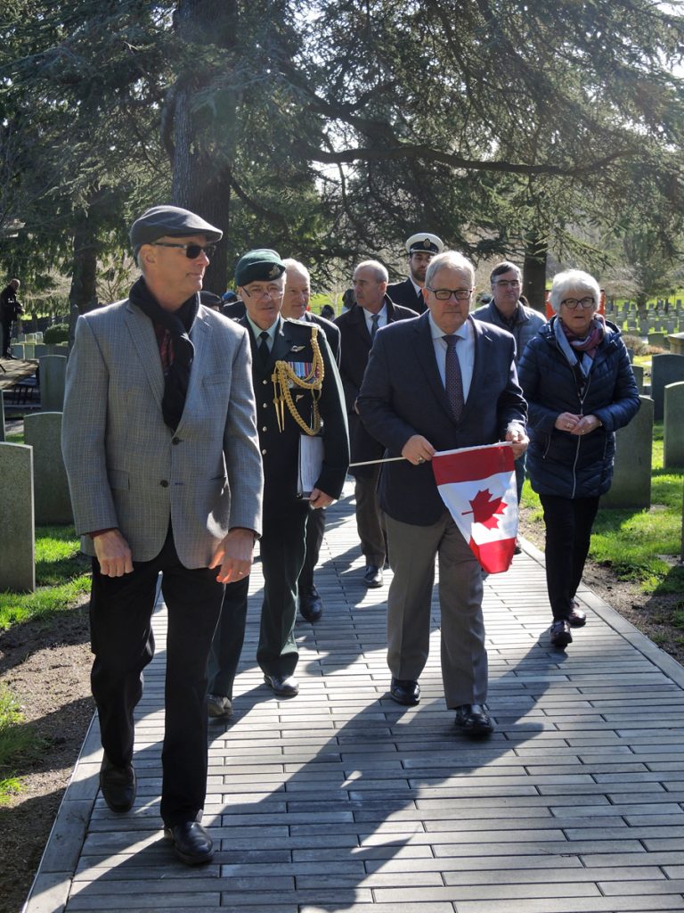Minister of Veterans Affairs Lawrence MacAulay carries a Canadian flag to lay at a gravesite in Veteran’s Cemetery. Photo by Peter Mallett