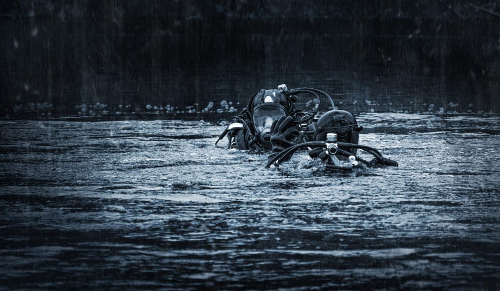 Two special forces scuba divers show each other the ok sign while preparing to dive.