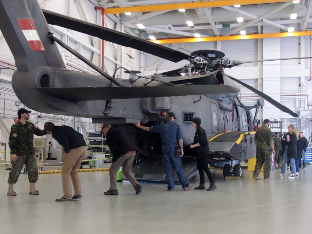 Family members learning the intricacies and details of the Sikorsky CH-148 Cyclone helicopter on display.
